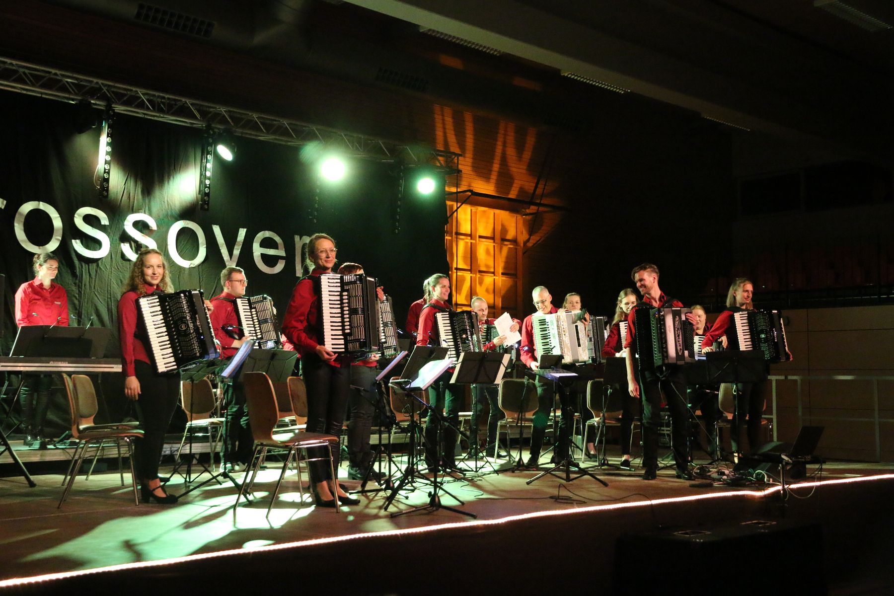 Das Orchester bei einem Konzertauftritt auf der Bühne, im Hintergrund der Schriftzug „Crossover“