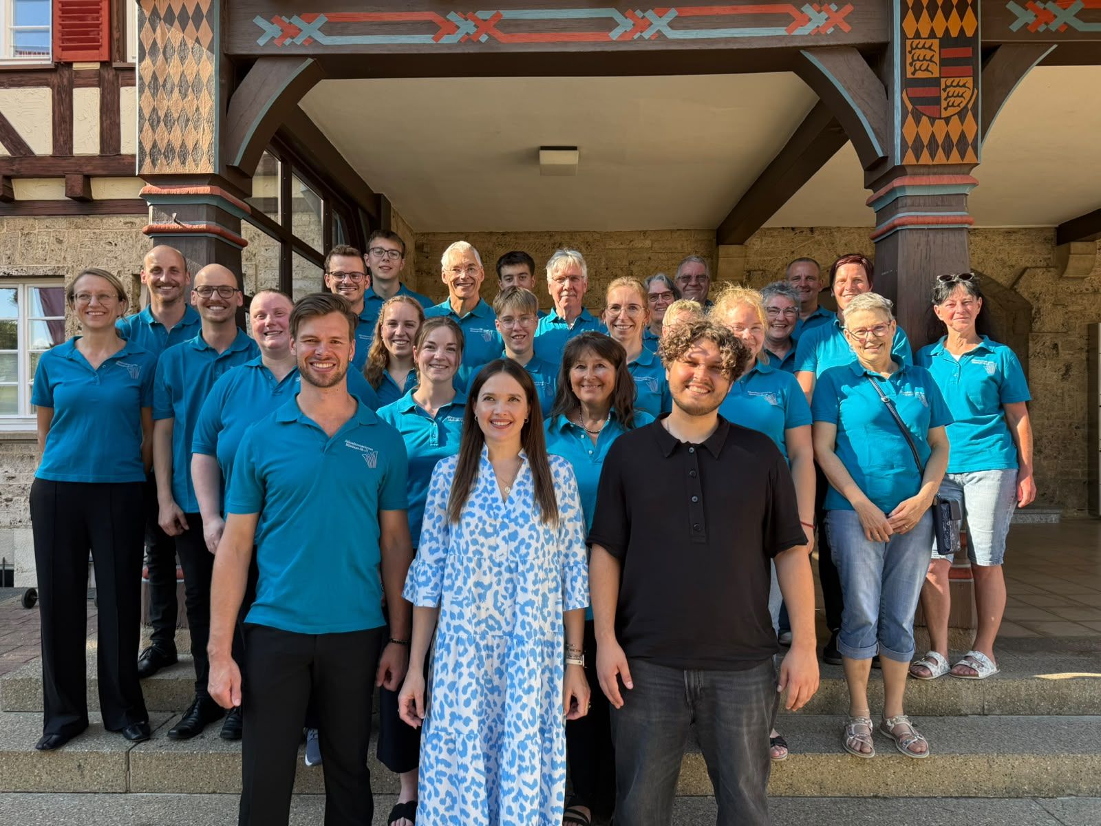 Gruppenbild des Akkordeonorchester Münsinger Alb in blauen Vereinshemden vor einem Fachwerkgebäude